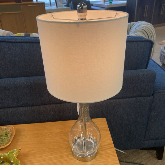 Table lamp with beige shade on a wooden table in a living room setting