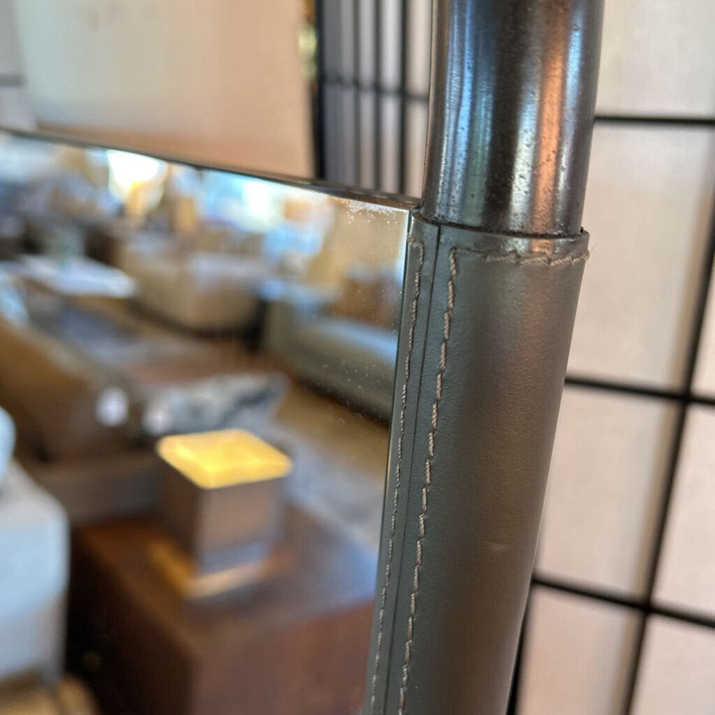 Close-up of a metallic pole with stitching detail, blurred indoor background