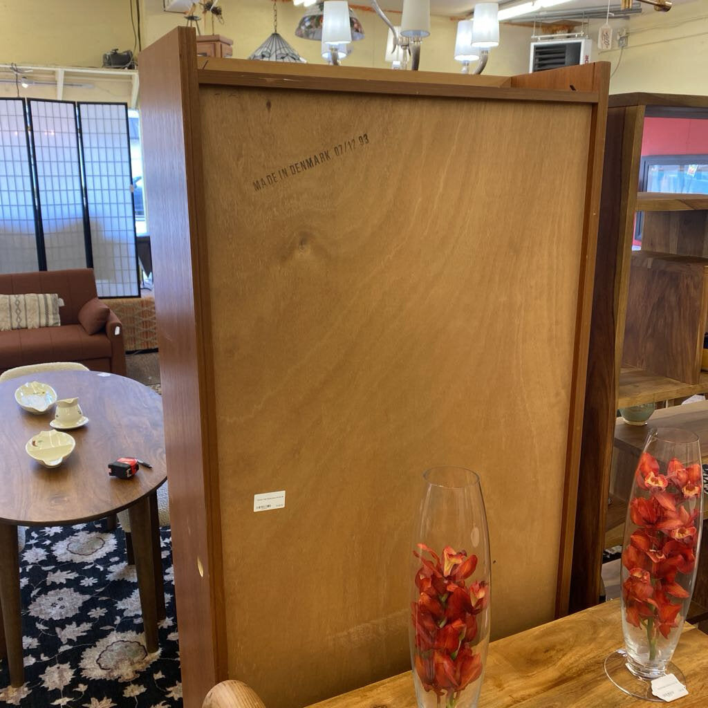 Wooden cabinet with 'Made in Denmark' inscription in a room setting.