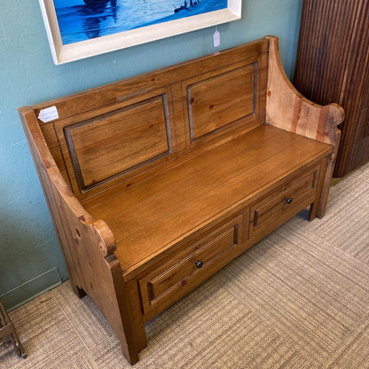 Wooden bench with storage drawers in a room with a blue wall and framed picture.