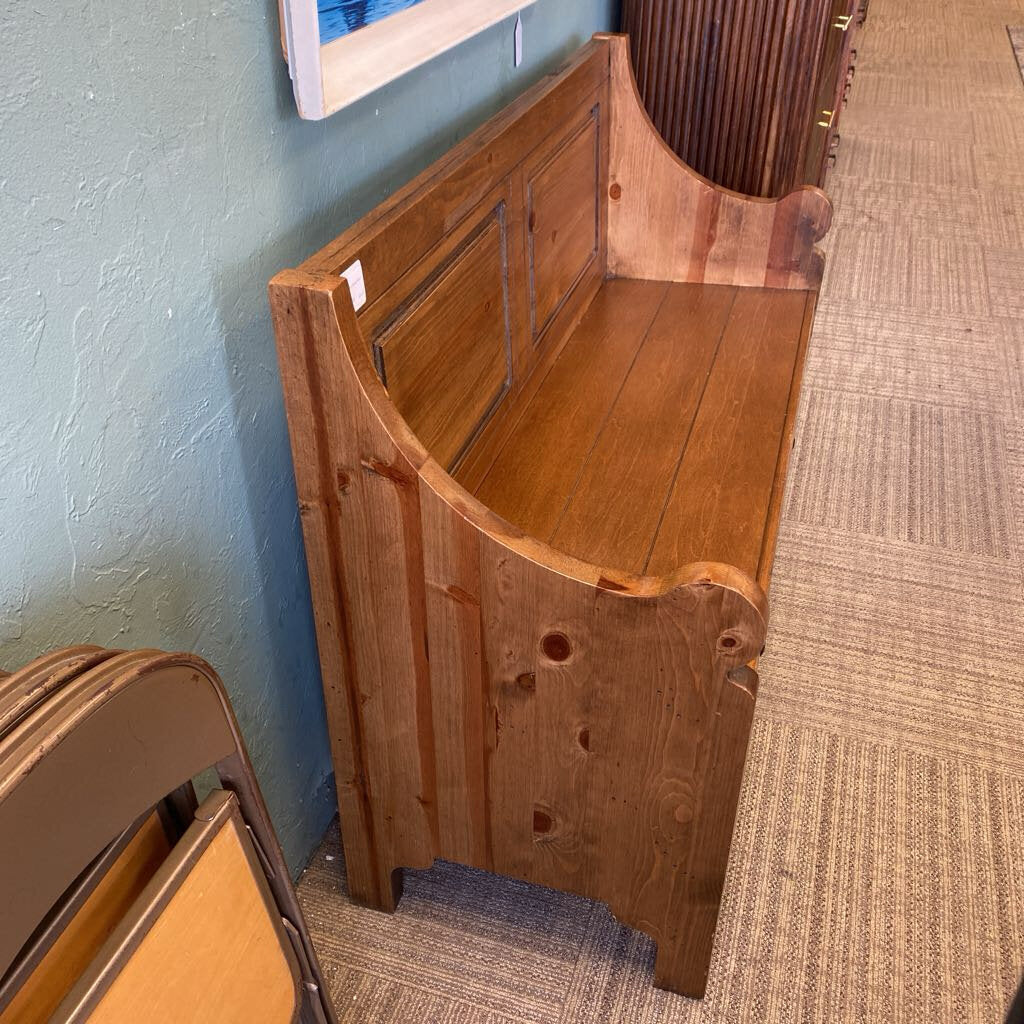 Wooden bench against a blue wall with a textured floor.