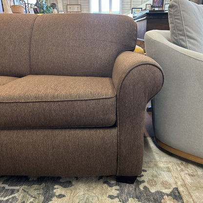 Brown sofa in a room with a patterned rug and other furniture.