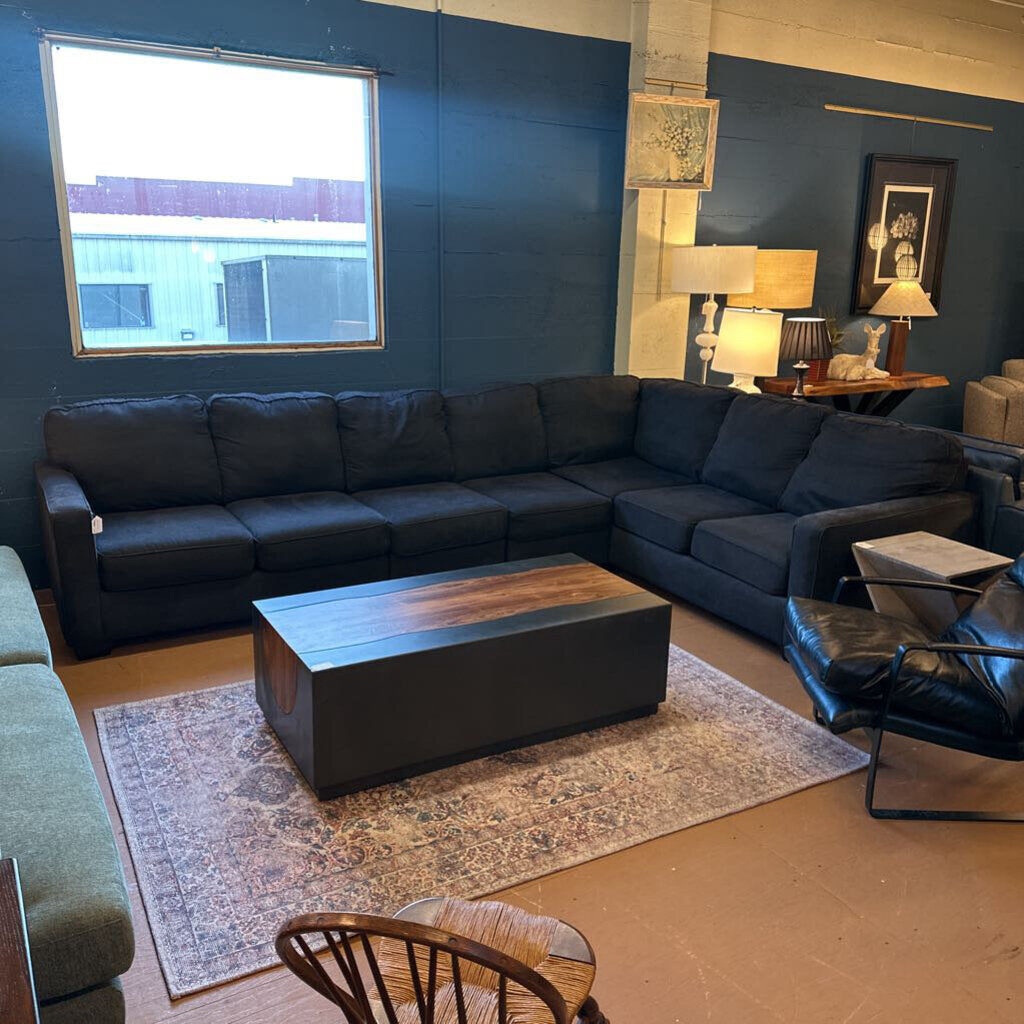 Living room with a dark blue sectional sofa, wooden coffee table, and decorative items.