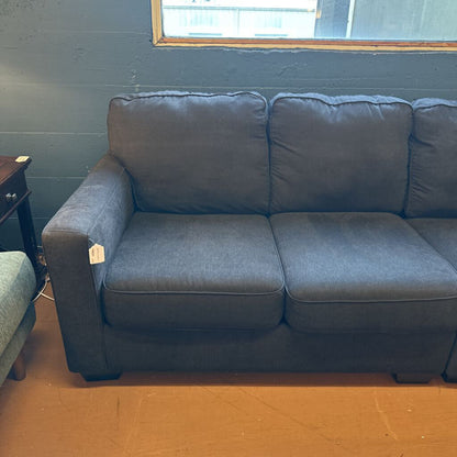 Gray sofa in a room with a window and wooden floor.
