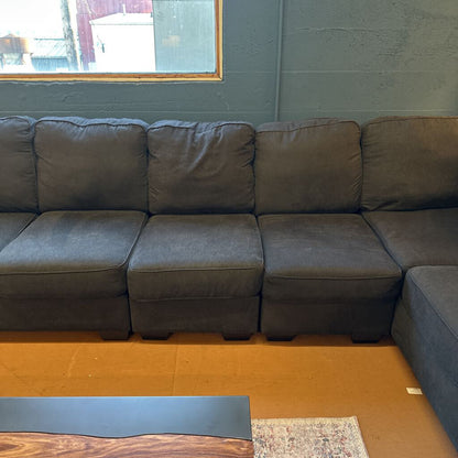 Gray sectional sofa in a room with a window and wooden floor.