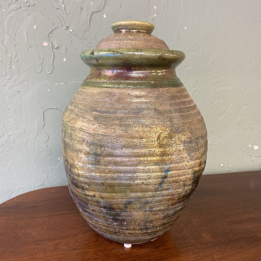 Stoneware urn with a textured surface on a wooden surface.