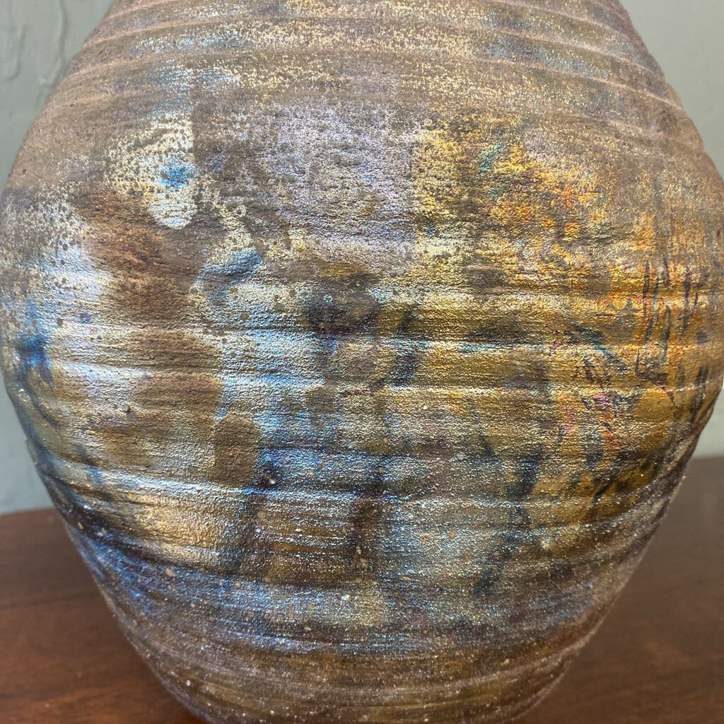 Textured ceramic vase on a wooden surface with a neutral background