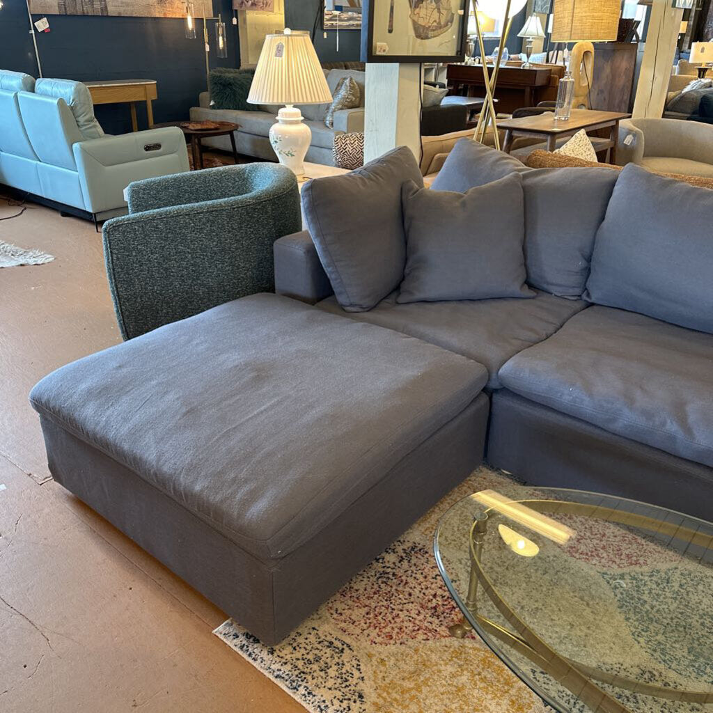 Gray sectional sofa in a showroom setting with other furniture.