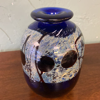 Blue glass vase with abstract patterns on a wooden surface