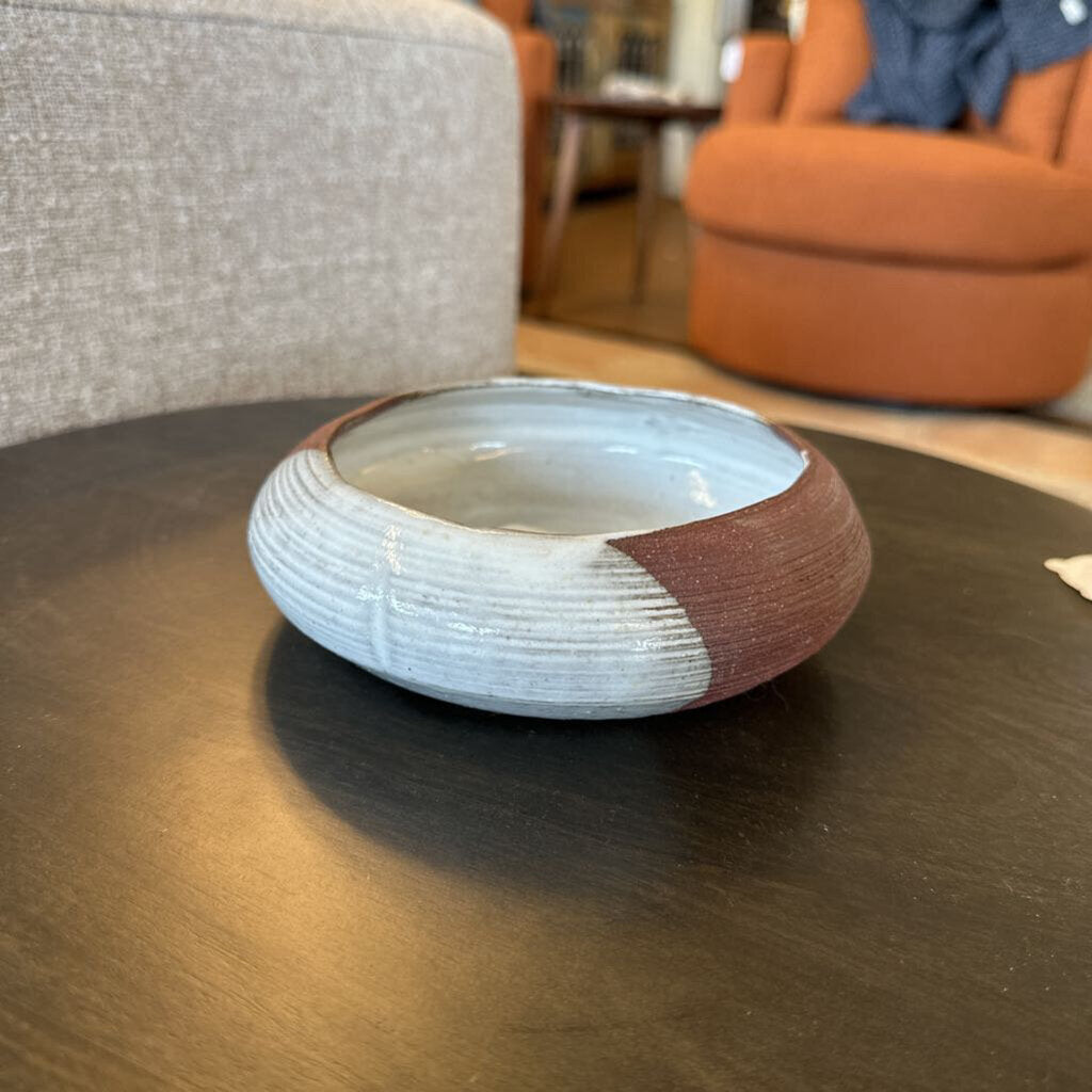 Ceramic bowl with two-tone design on a wooden table in a living room setting