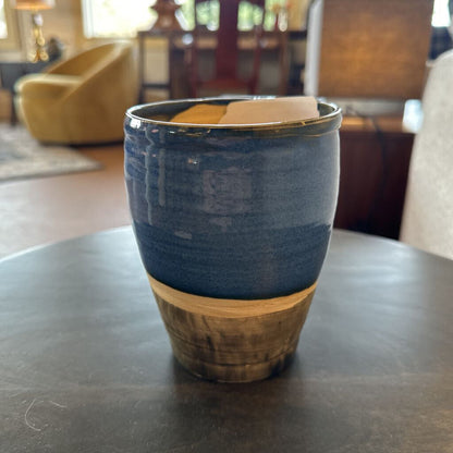 Blue ceramic mug with wooden base on a dark surface, blurred indoor background