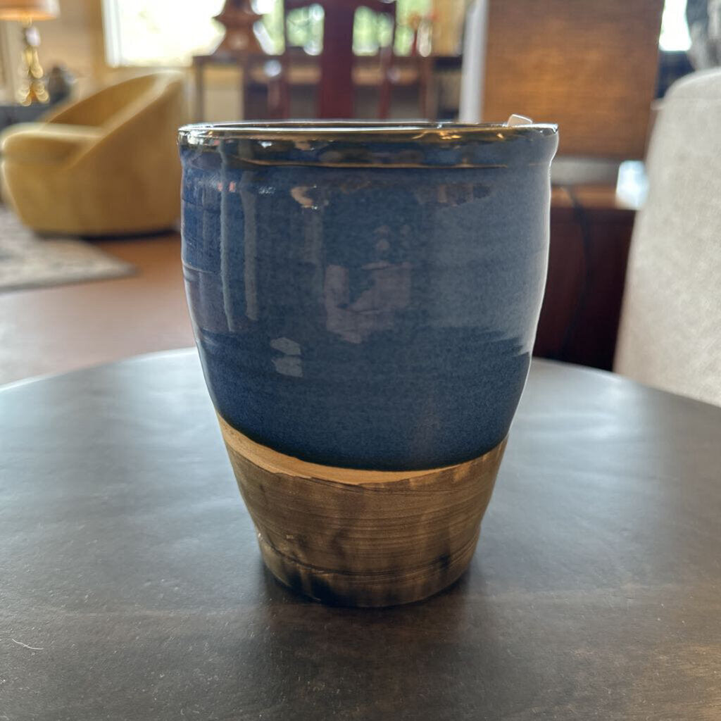 Blue ceramic tumbler with wooden base on a dark surface