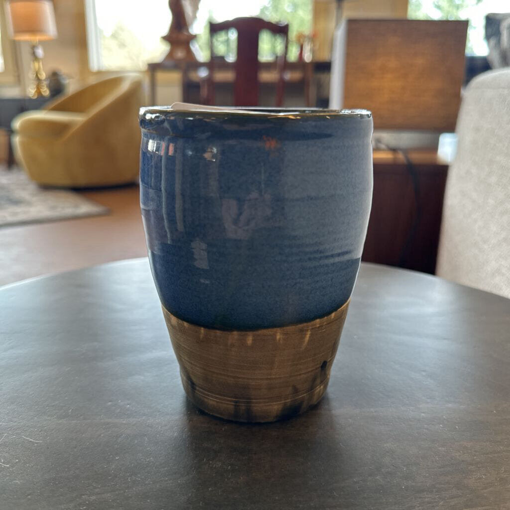 Blue ceramic tumbler on a dark surface with a blurred indoor background