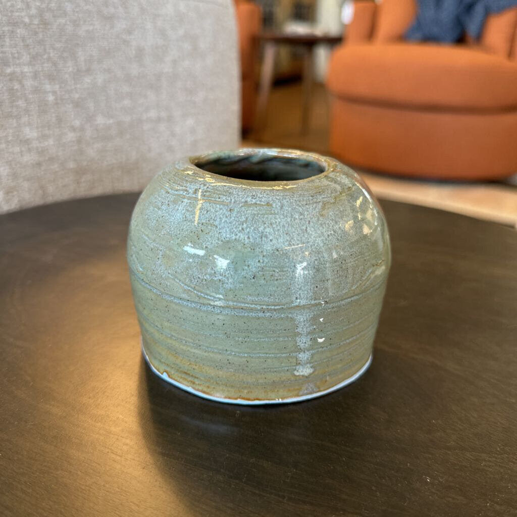 Ceramic vase on a wooden table with a blurred indoor background