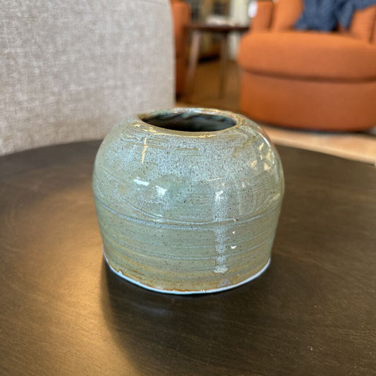 Ceramic vase on a wooden table with a blurred indoor background