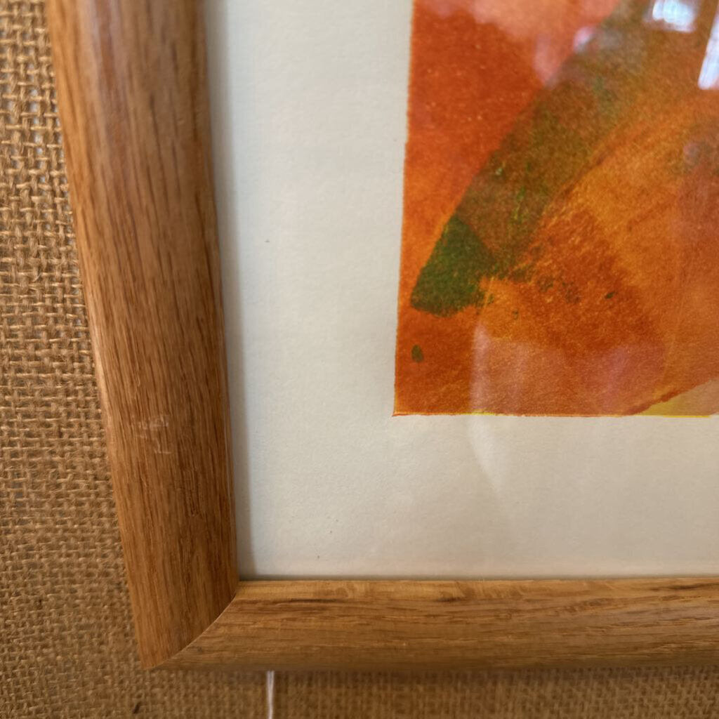 Close-up of a wooden frame with a piece of paper or artwork inside, on a textured surface.