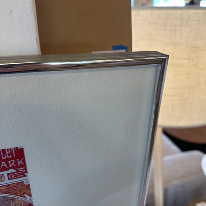 Framed artwork with a visible brand logo on a white wall.