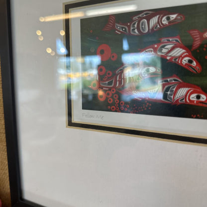 Framed artwork with red and green abstract design on a white wall.