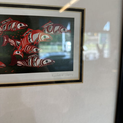 Framed artwork of red fish with black frame on a light-colored wall.