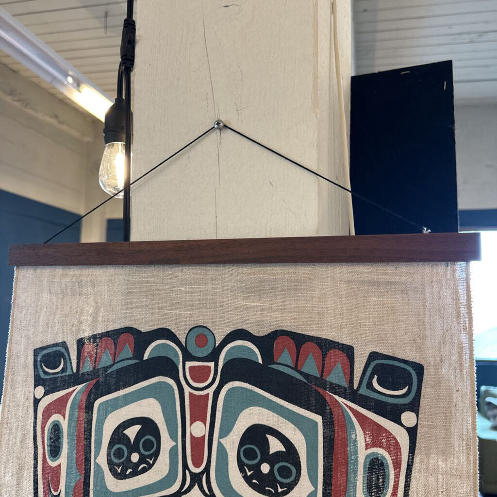 Decorative fabric with tribal design hanging on a stand indoors