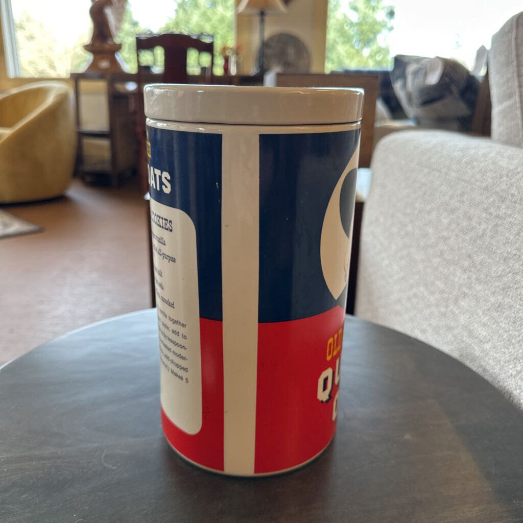 Canister with a blue and red design on a table in a room with furniture and a window.