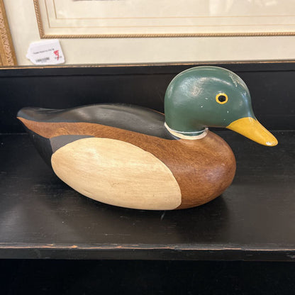 Wooden duck decoy on a dark surface with a blurred background