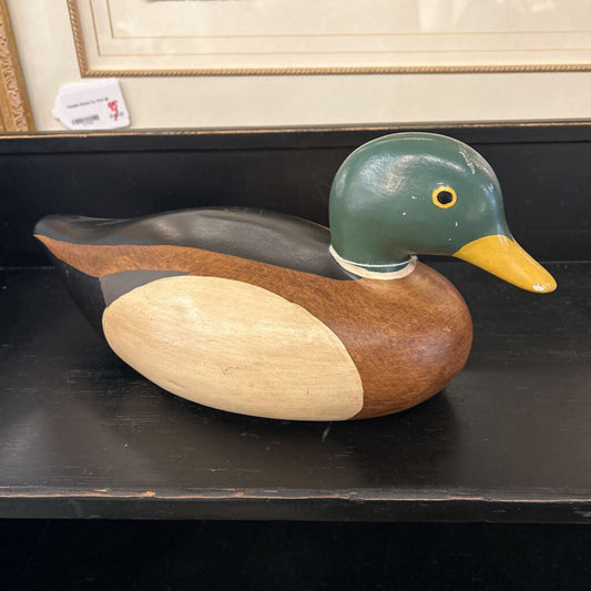 Wooden duck decoy on a dark surface with a blurred background