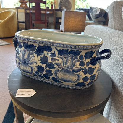 Blue and white floral-patterned ceramic pot on a wooden table in a living room.