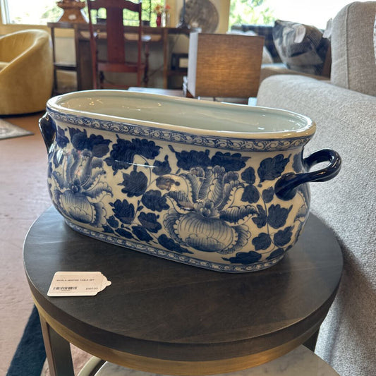 Blue and white floral-patterned ceramic pot on a wooden table in a living room.