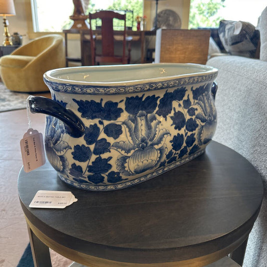Blue and white floral-patterned ceramic planter on a wooden table with tags, in a home setting.