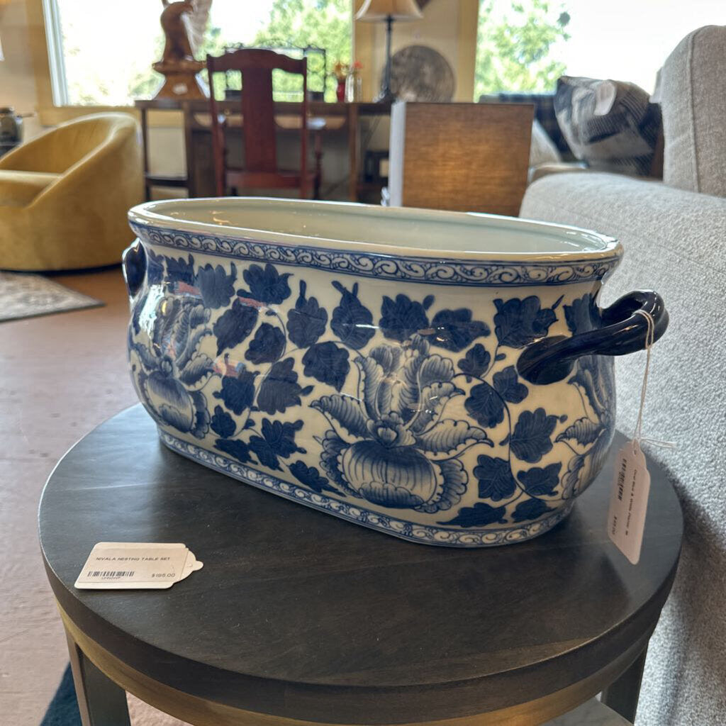 Blue and white floral-patterned pot on a round wooden table in a living room.