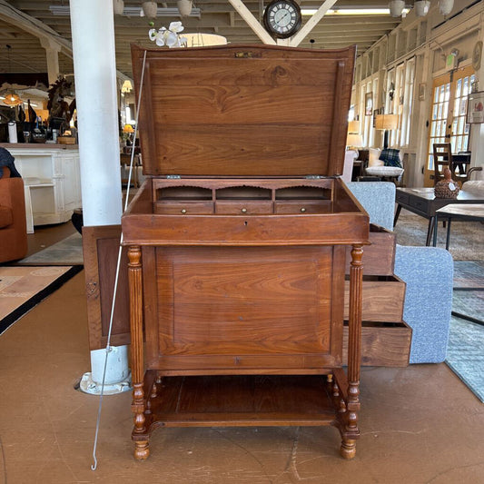 Wooden desk with a hinged top in an indoor setting