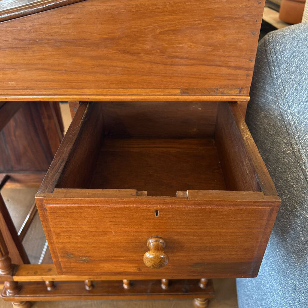 Wooden drawer unit with an open drawer on a carpeted floor.