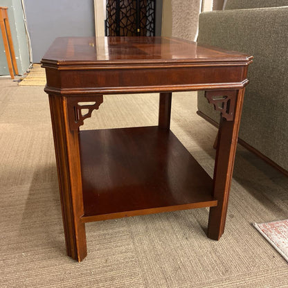 Wooden side table in a room with carpeted floor and furniture.