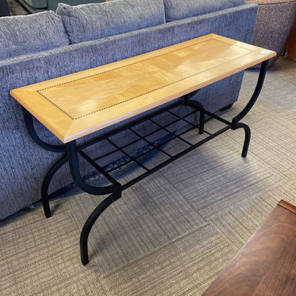 Wooden table with metal legs in a room with a blue sofa and wooden floor.