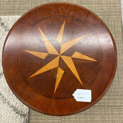 Wooden round table with star design on a textured surface