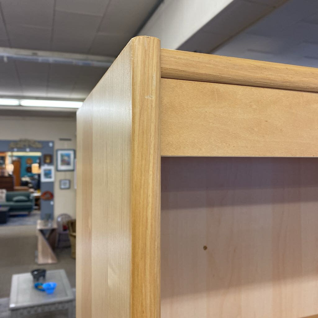 Close-up of a wooden shelf with a blurred indoor setting in the background