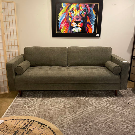 Gray sofa in a room with a colorful lion painting on the wall.