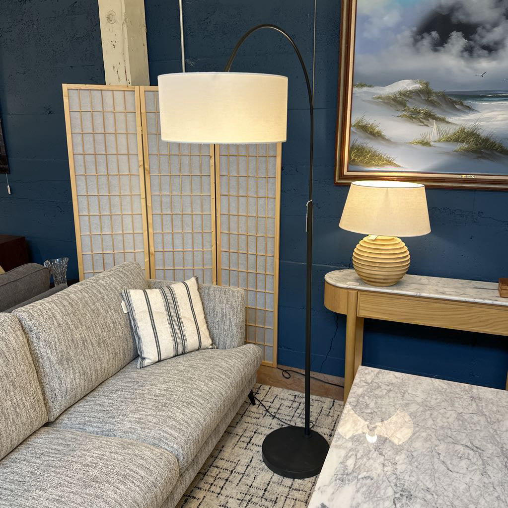 Living room with gray sofa, floor lamp, and wall art