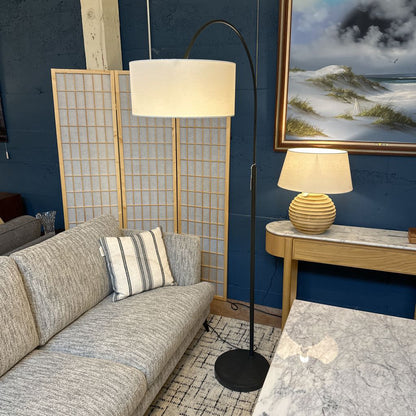 Living room with gray sofa, floor lamp, and wall art