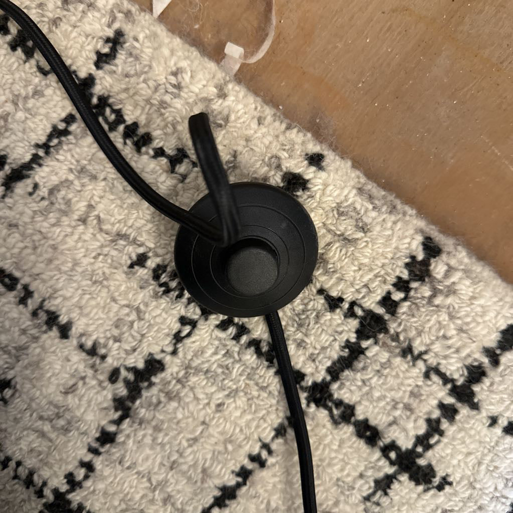 Black earbud on a textured surface with a cardboard box in the background