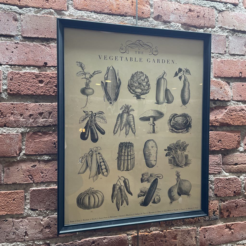 Framed vintage-style illustration of vegetables on a brick wall.