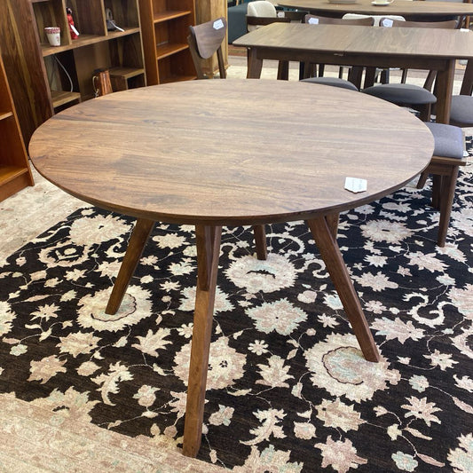 Round wooden table on a patterned rug with chairs around it