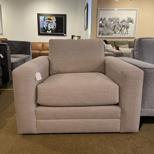 Beige armchair in a showroom with other furniture and wall art.