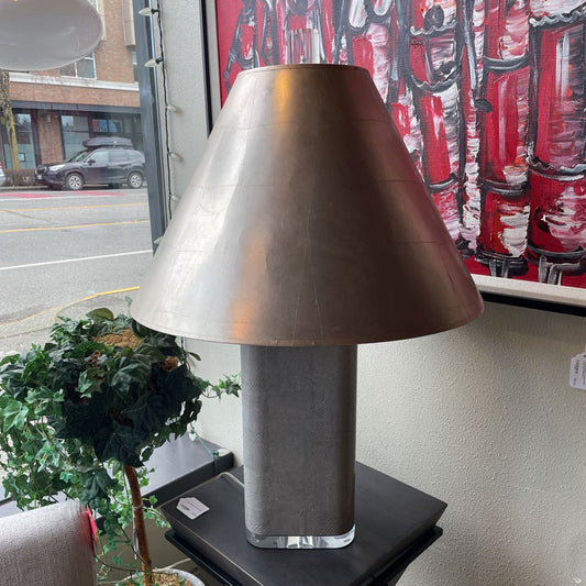 Table lamp with a metallic shade on a surface near a window with street view