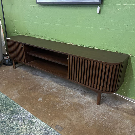 Wooden TV stand against a green wall