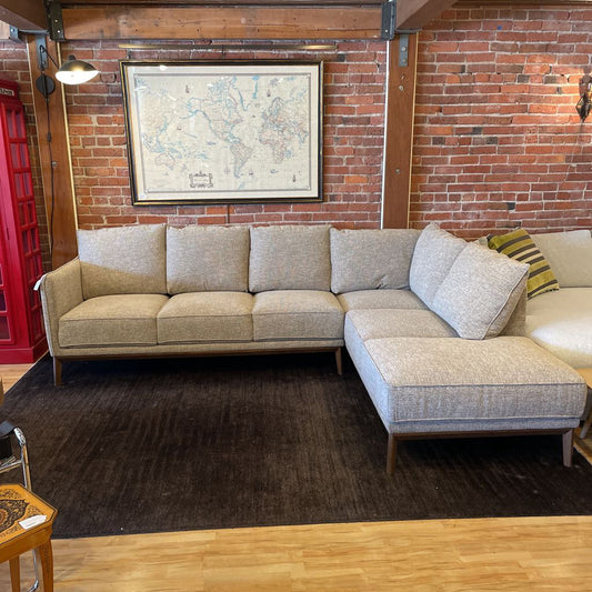 Gray sectional sofa in a room with brick walls and a map.