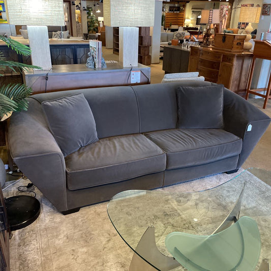 Gray sofa in a showroom with a glass table and chairs.