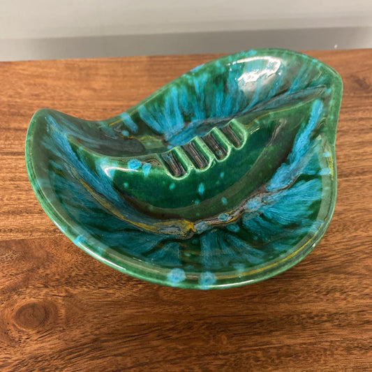 Ceramic leaf-shaped bowl with blue and green glaze on a wooden surface