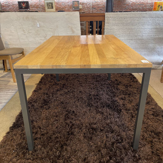 Wooden table with metal legs on a brown rug in an indoor setting